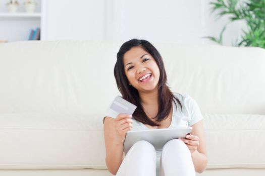 Woman laughs while she is holding a card and a tactile tablet in a living room