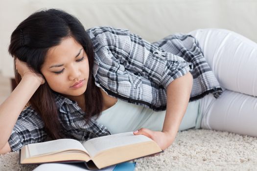 Woman reading a book as she lays on the floor in a living room