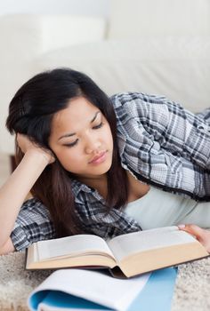 Close-up of a woman reading a book as she lays on the floor in a living room