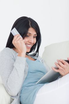 Smiling woman holding a credit card and a tablet in a living room