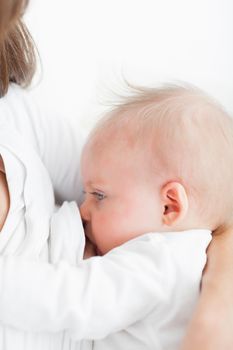 Mother breastfeeding her baby against a white background