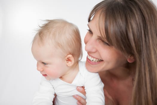 Laughing woman holding her cute daughter against a grey background