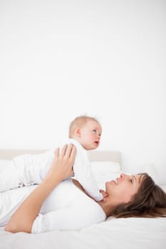 Cheerful woman holding her cute little girl in a bedroom
