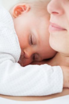 Baby napping on the chest of her mother indoors