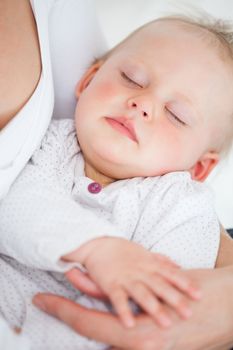 Cute baby closing her eyes while being held in a room