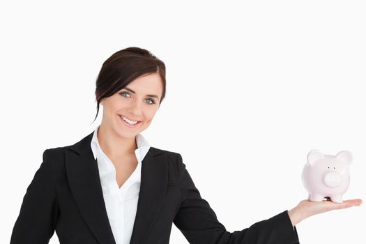 Smiling businesswoman with a piggy-bank on her palm against white background