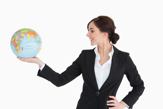 Brunette businesswoman holding an earth globe in her palm against white background
