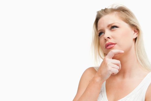 Attractive blonde woman lost in thoughts against a white background