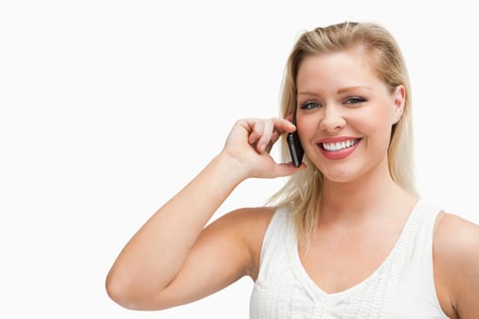 Smiling blonde woman holding a cellphone against a white background