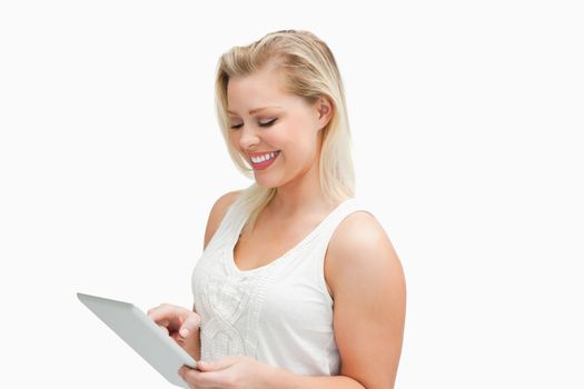 Smiling blonde woman using her tablet computer against a white background