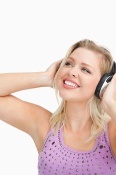 Cheerful woman wearing headphones against a white background