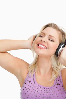 Blonde woman leaning her head while listening to music against a white background