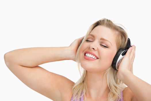 Woman listening to music while closing her eyes against a white background