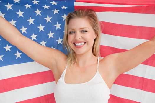 Smiling woman raising the American flag in a studio