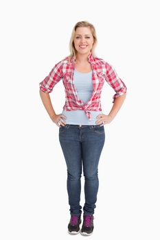 Happy young woman placing her hand on her hips against a white background