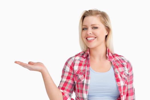 Blonde woman beaming while placing her hand palm up against a white background