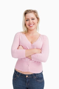 Smiling blonde crossing her arms while standing against a white background