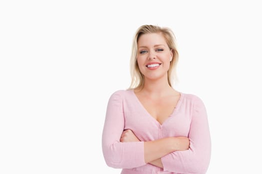 Happy blonde woman crossing her arms against a white background