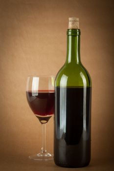 A bottle of red wine and a glass half full on a vintage orange background.