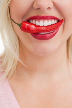 Happy woman placing a red chili in her mouth against a white background