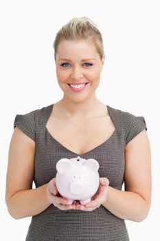 Woman showing a pink piggy bank against white background