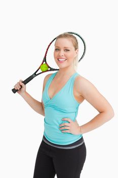 Woman smiling while holding a racquet behind her head against white background