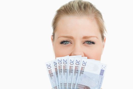 Woman hiding her mouse with her euros banknotes against white background