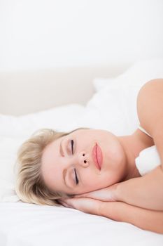 Young woman sleeping with a smile in her bed