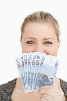 Woman hiding a middle of her face with euro banknotes against white background
