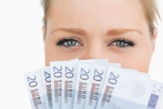 Close up of a woman face hidden with euro banknotes against white background