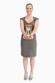 Woman holding a hourglass against white background