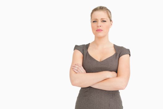 Uneasy woman standing with her arms crossed against white background