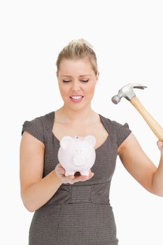 Serious woman with a piggy bank and a hammer against white background