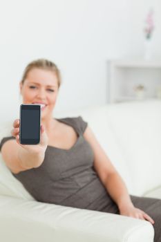 Woman showing a screen of a smartphone sitting on a sofa