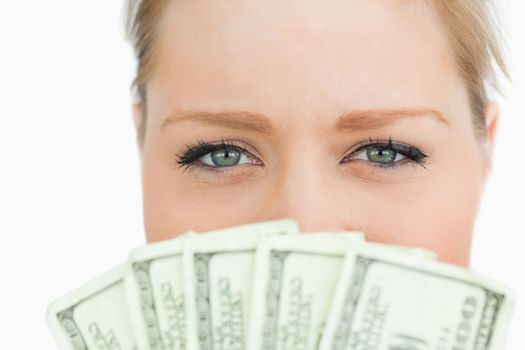 Close-up of a woman face hidden with dollars banknotes against white background