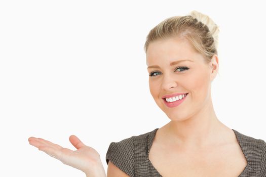 Smiling woman presenting something with her hand against white background