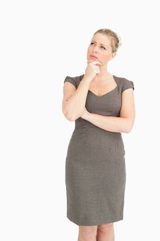 Woman standing with a finger on her chin against white background