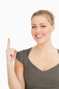 Pretty woman pointing something with her finger against white background