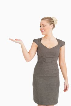 Woman smiling presenting something with her hand against white background