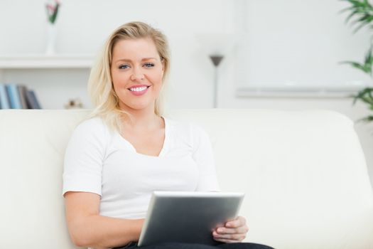Casual woman sitting on a sofa using an ebook in a lounge