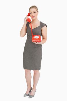 Serious woman calling with a retro phone against white background