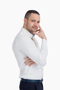Man standing up while holding his chin with his hand against a white background