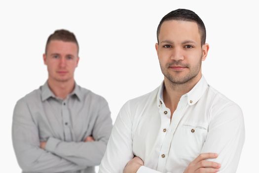 Two men standing while crossing their arms against a white background