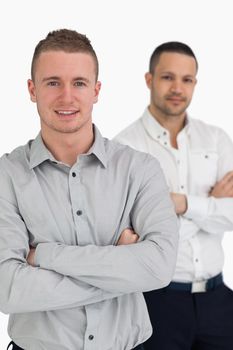 Two men smiling while crossing their arms against a white background