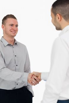 Smiling men shaking hands against a white background