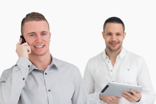 Two men with phone and tablet computer against a white background