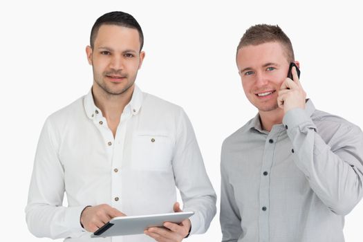 Two smiling men with a phone and a tablet computer against a white background