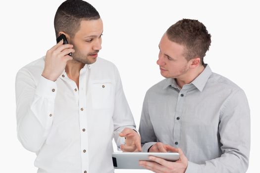 Two people discussing while phoning and holding a tablet computer against a white background