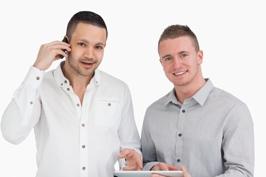 Smiling men holding a phone and a tablet computer against a white background