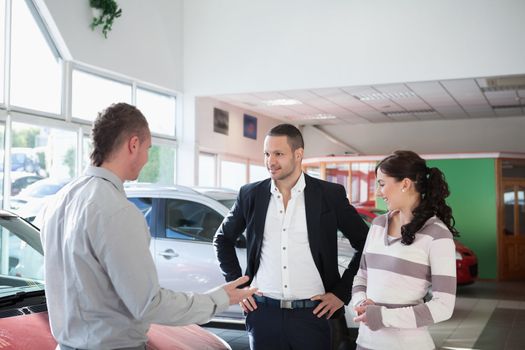 Couple with a car dealer in a car shop